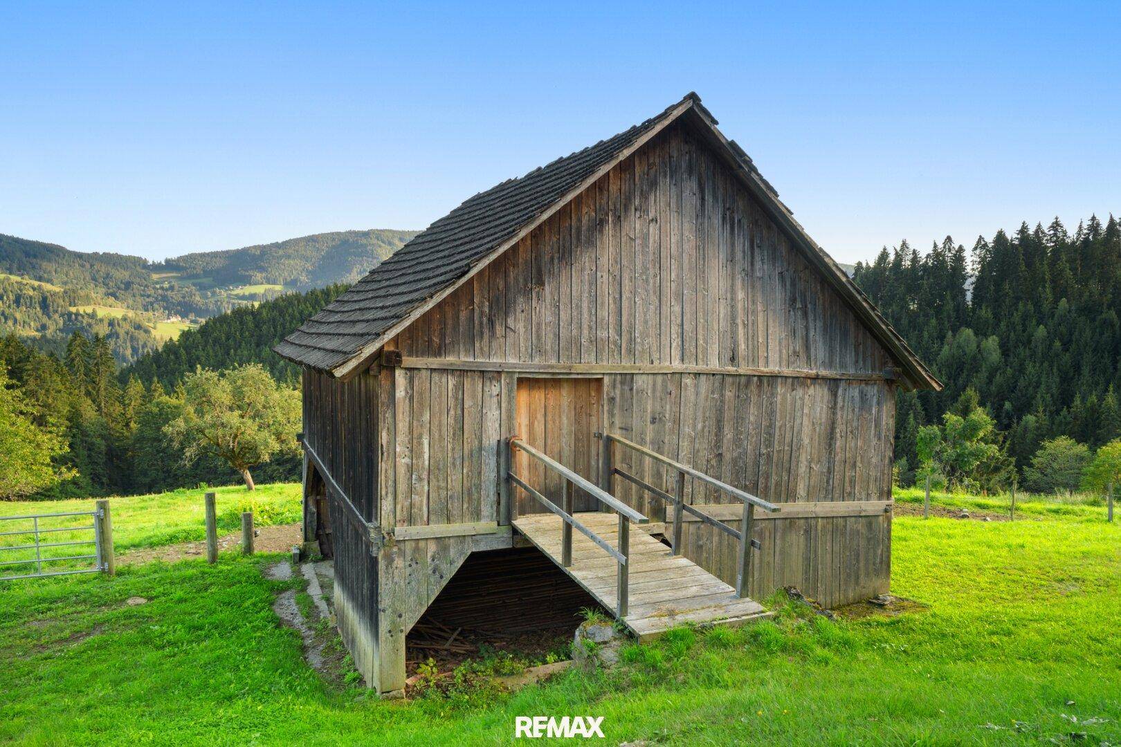 Rustikale Holzscheune mit traditionellem Holzdach und einer Rampe, die zum oberen Eingang führt.