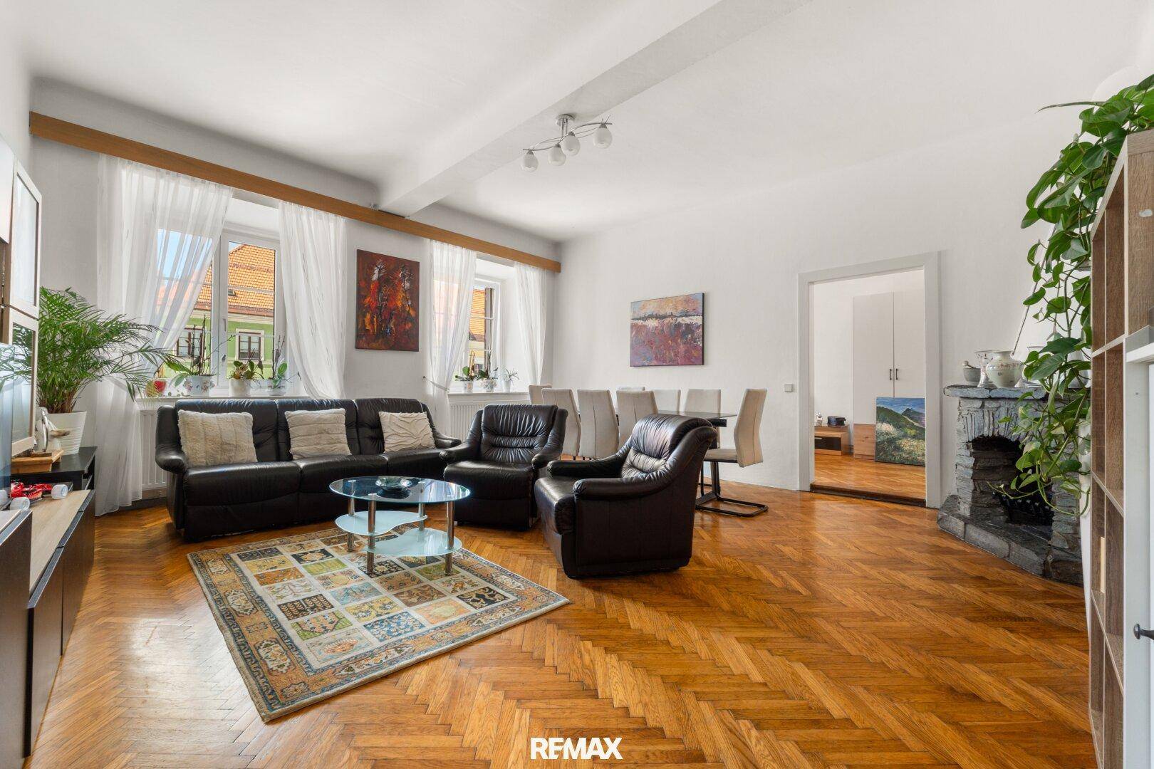 Geräumiger Wohn- und Essbereich mit Fischgrätparkett, Ledersofas und Steinkamin.