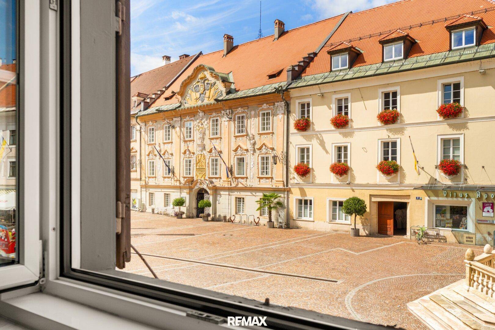 Blick aus dem Fenster auf einen historischen Stadtplatz mit prächtigen Gebäuden.