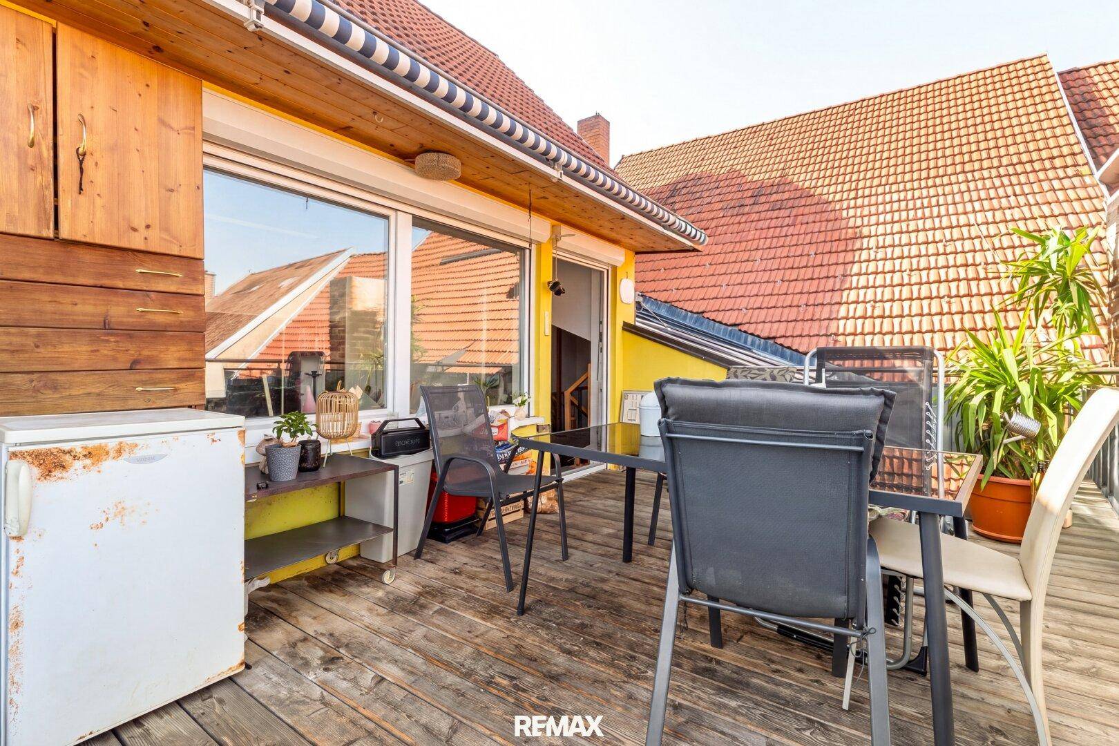 Geräumige Dachterrasse mit Holzboden, Außenkühlschrank und Markise für Schatten.