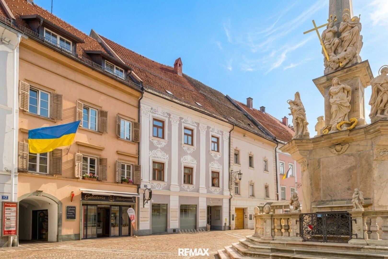 Historische Gebäudezeile in der Altstadt mit einem Denkmal und traditioneller Architektur.