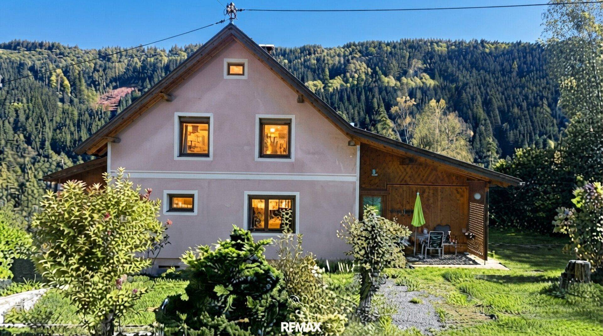 Rückseite des Hauses mit kleiner überdachter Terrasse und Blick auf die bewaldeten Hügel.
