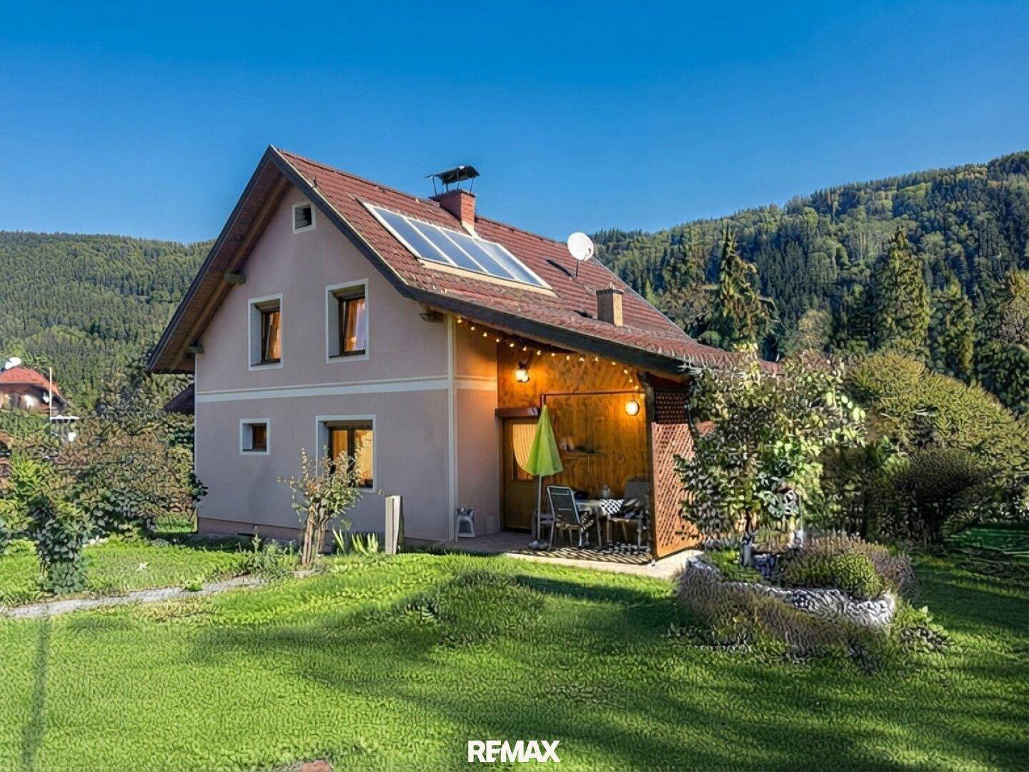 Haus mit Solaranlage auf dem Dach und einer gemütlichen, überdachten Terrasse im Grünen.
