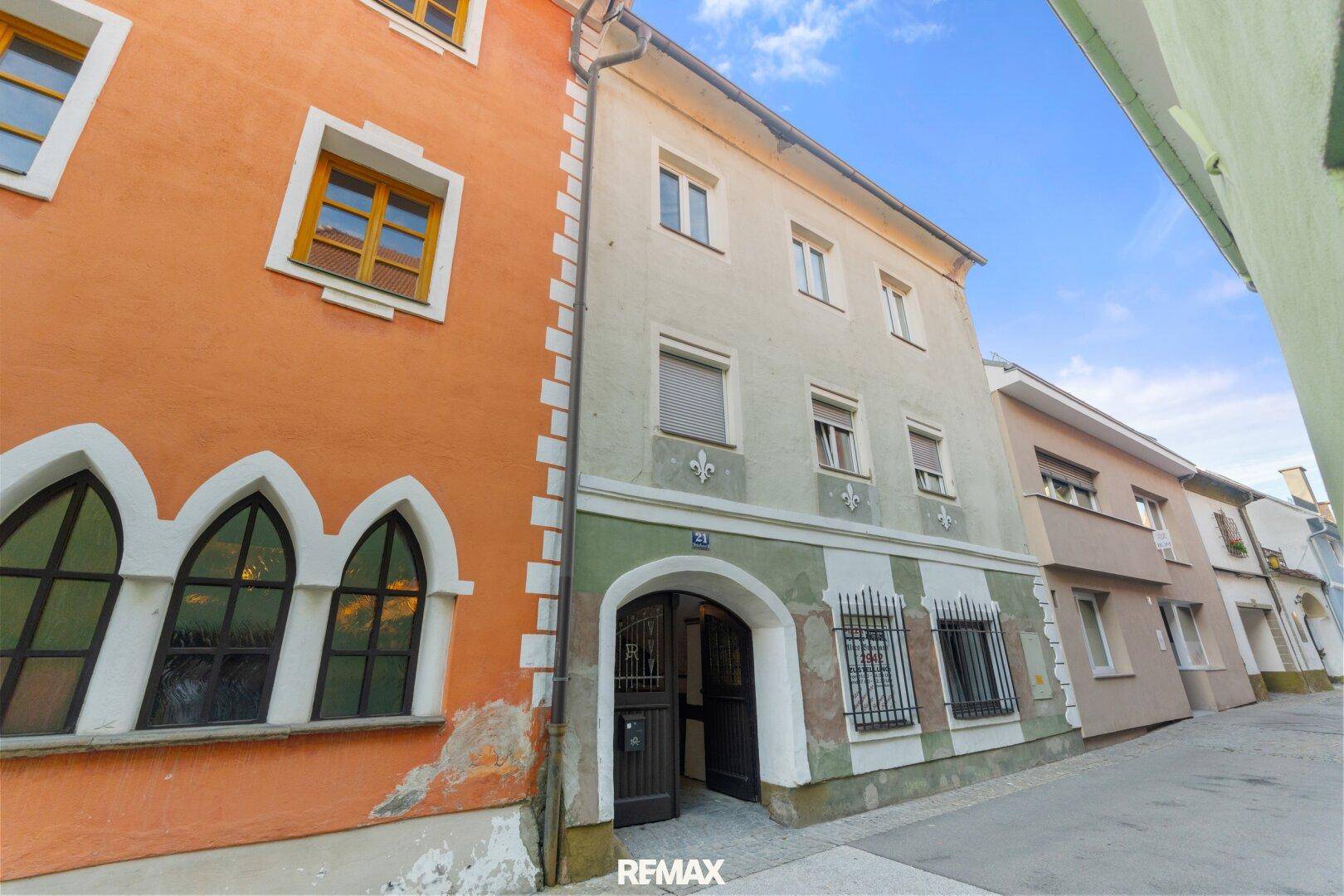 Historische Gebäudefassade mit einem gewölbten Eingang und traditionellen Fenstern in einer engen Gasse.