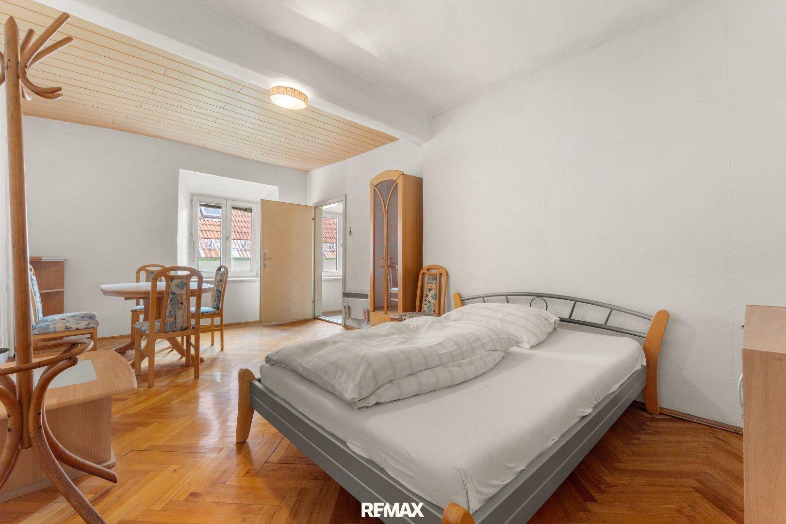 Gemütliches Schlafzimmer mit Holzboden, Holzdecke und einem kleinen Essbereich, hell und einladend.