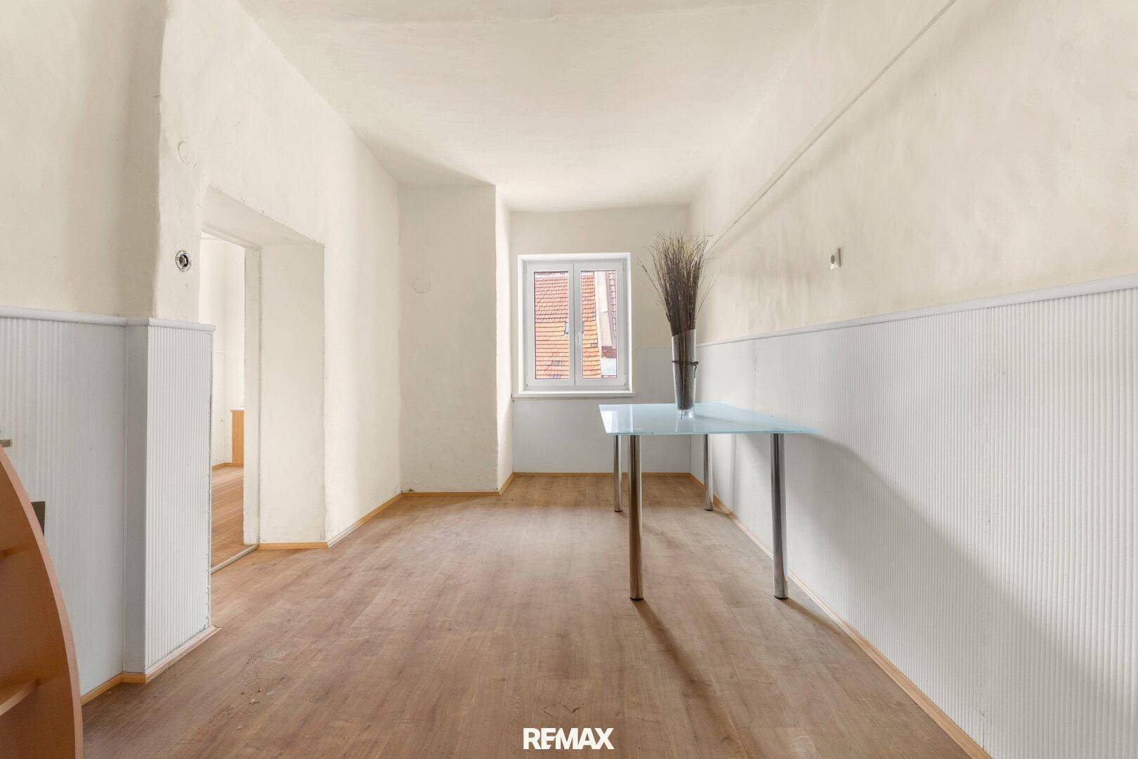 Heller, leerer Raum mit Holzboden und weiß getäfelten Wänden, ideal für individuelle Gestaltung.