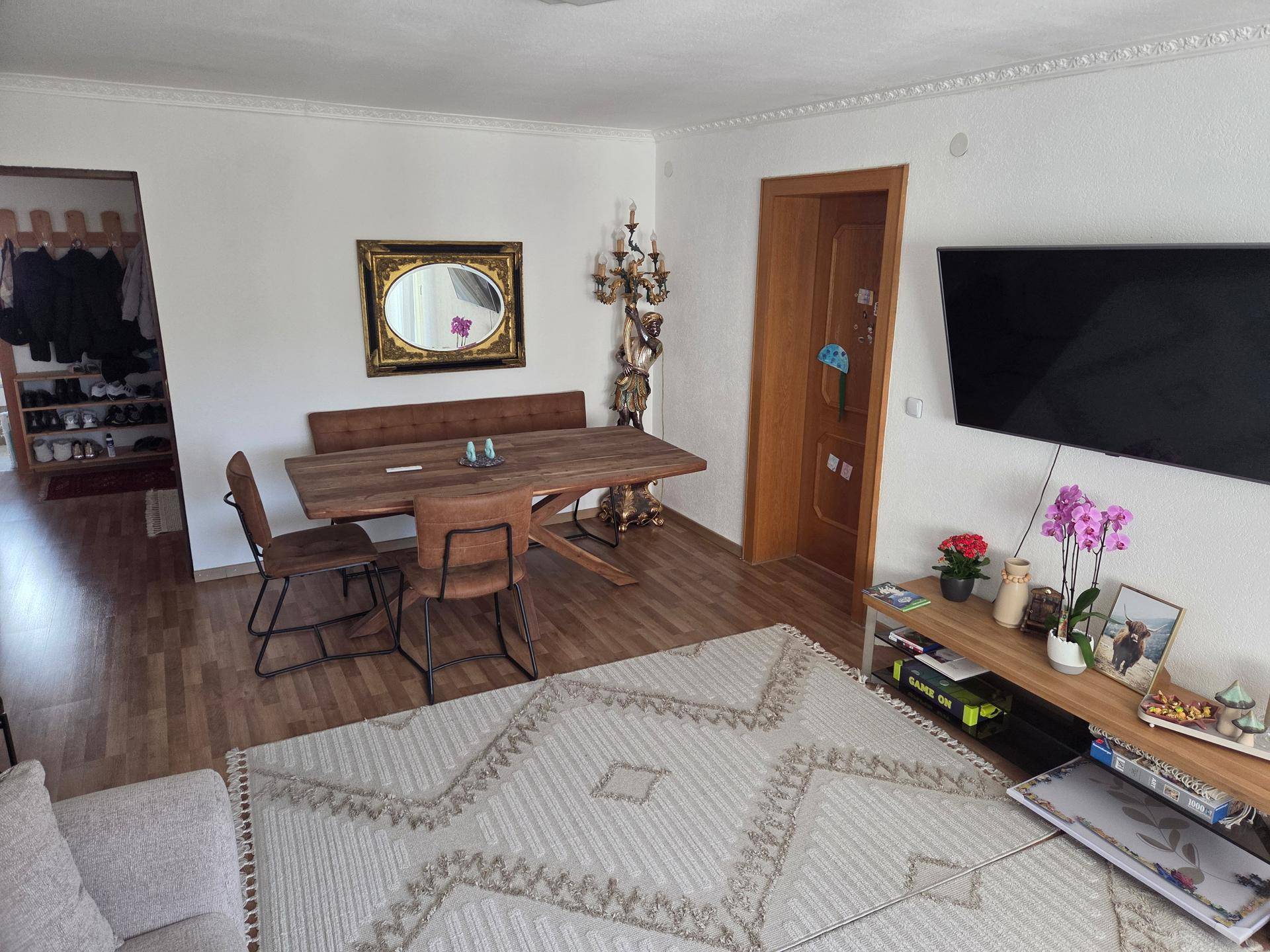 Gemütlicher Wohn- und Essbereich mit Holztisch, Bank und Fernseher.