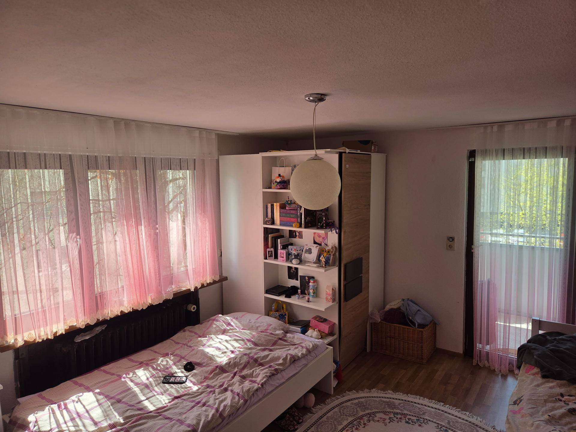 Schlafzimmer mit Einzelbett, Kleiderschrank und Zugang zum Balkon.