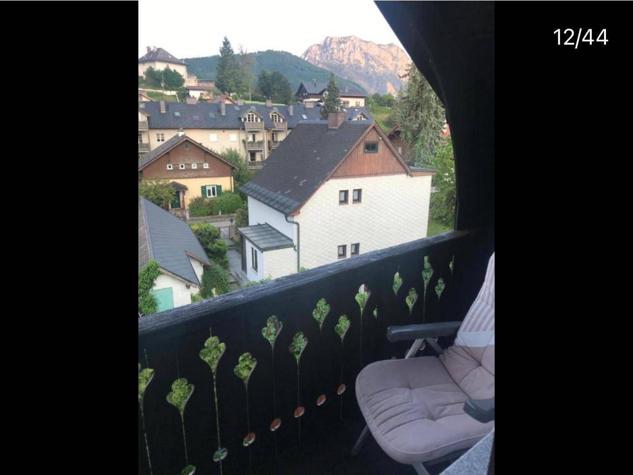 Balkon mit Sitzgelegenheit und malerischem Blick auf die umliegenden Häuser und Berge.
