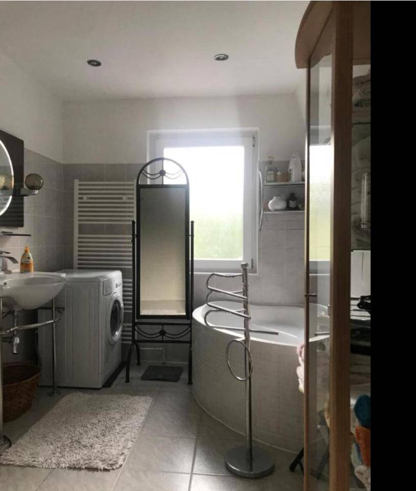 Geräumiges Badezimmer mit Waschmaschine, Badewanne, Waschbecken und beheiztem Handtuchhalter.