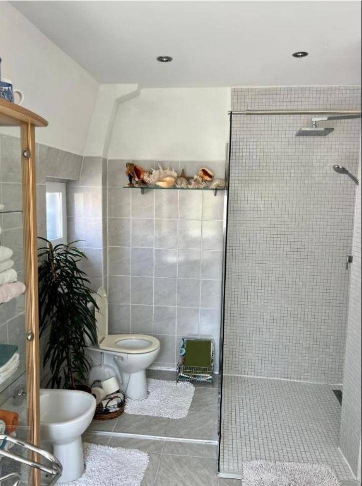 Modernes Badezimmer mit begehbarer Dusche, Toilette, Bidet und Fenster für Tageslicht.