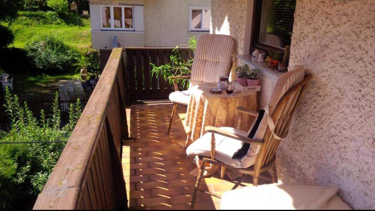 Sonniger Balkon mit bequemen Gartenmöbeln und Blick ins Grüne.