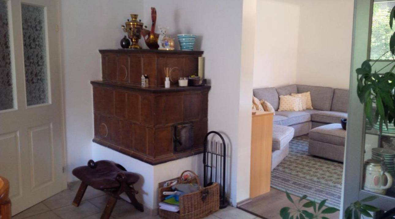 Eingangsbereich mit traditionellem Kachelofen und offenem Übergang zum Wohnzimmer.