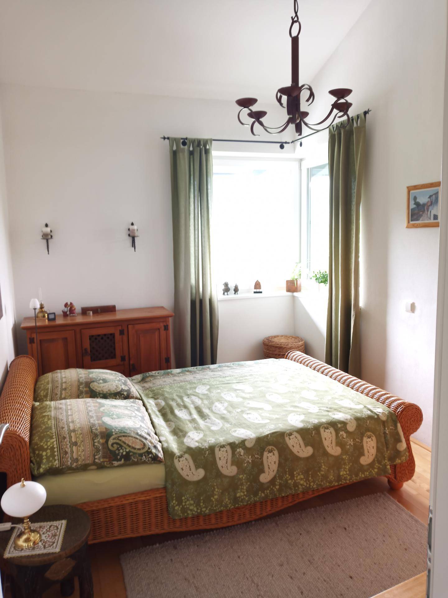 Gemütliches Schlafzimmer mit Rattanbett, Holzmöbeln und traditionellem Kronleuchter.