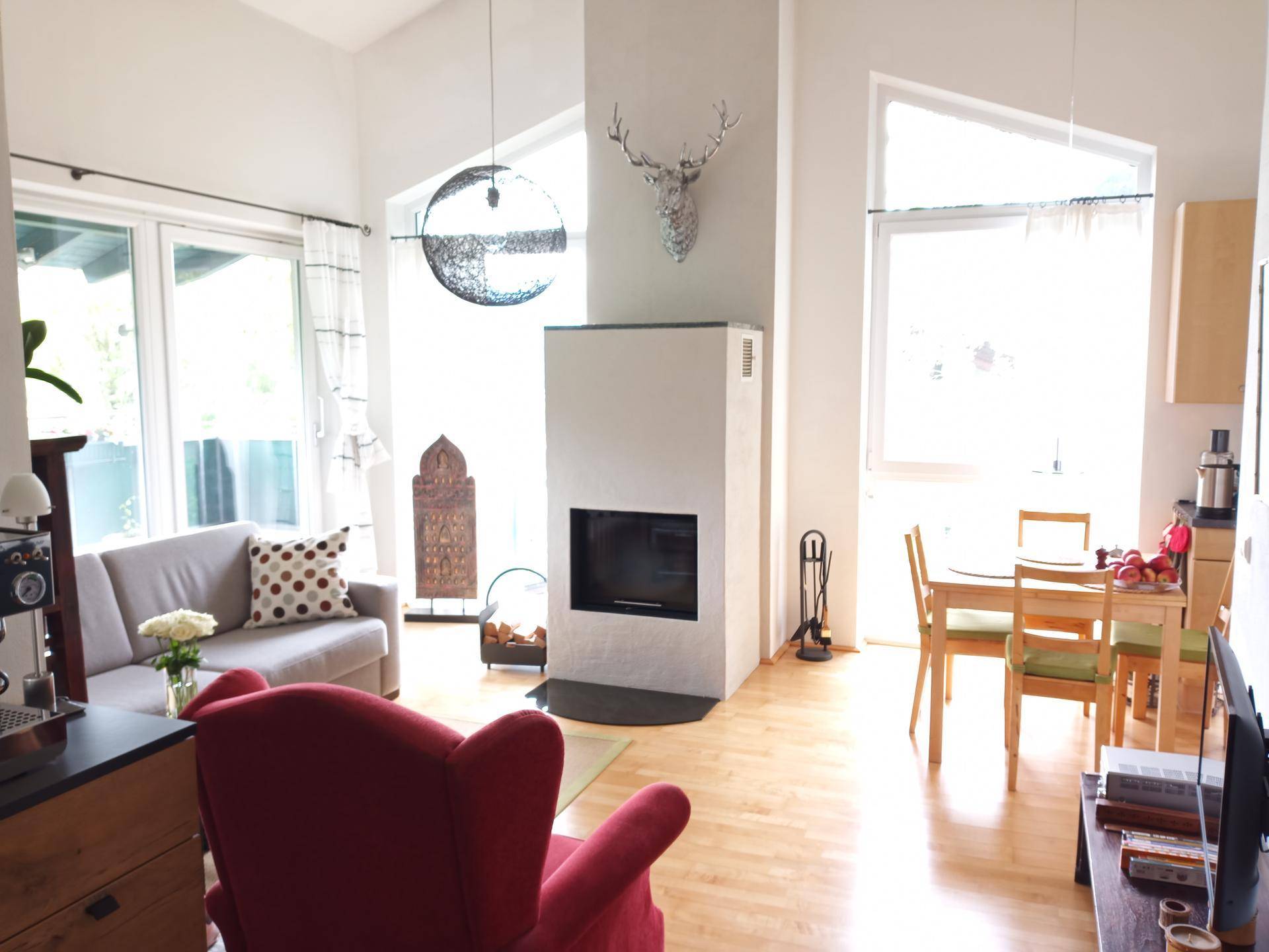 Helles Wohn-Esszimmer mit Kamin, hohen Decken und Holzboden.