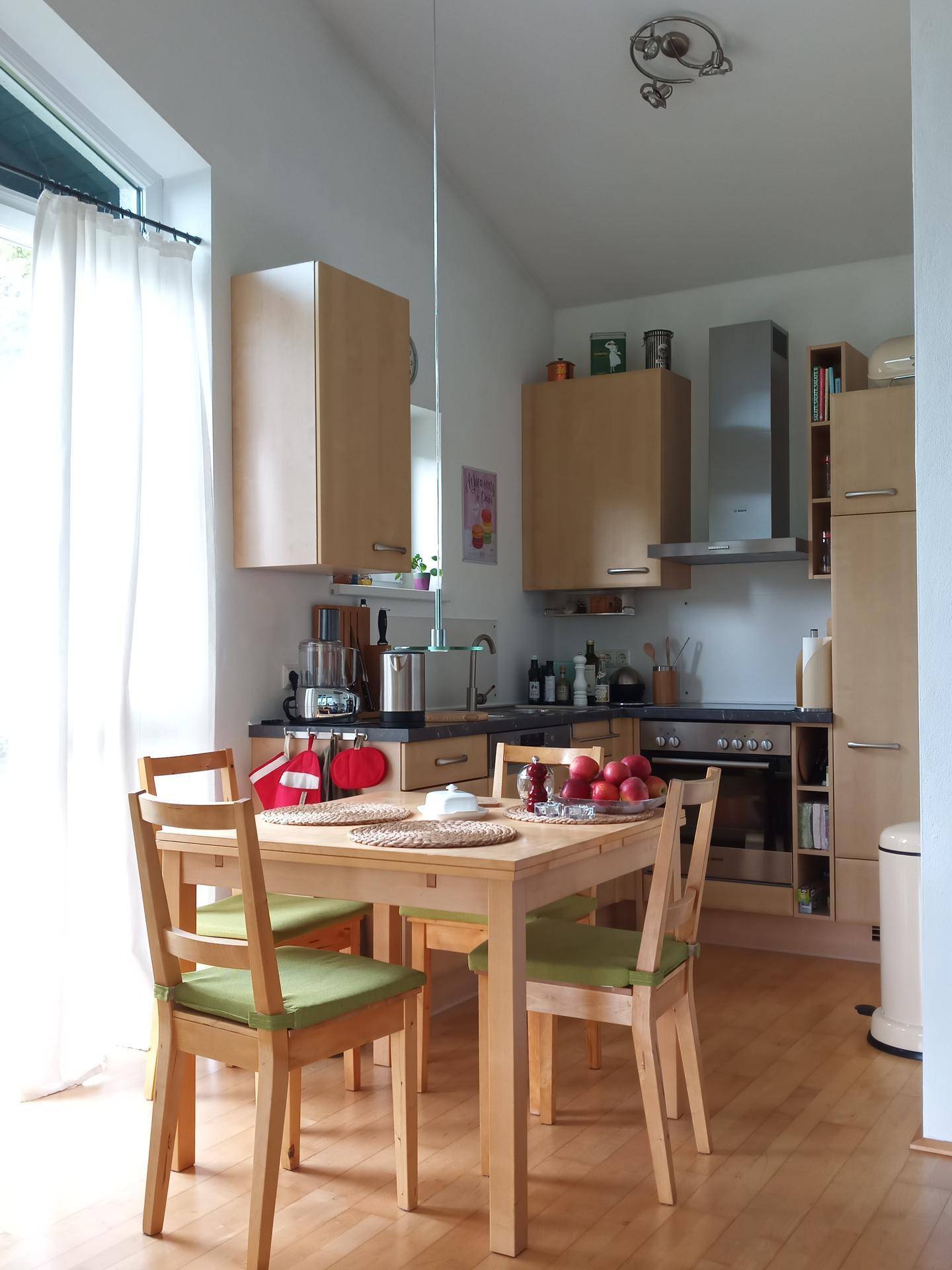 Funktionale Küche mit Esstisch, hellen Holzschränken und Zugang zum Außenbereich.