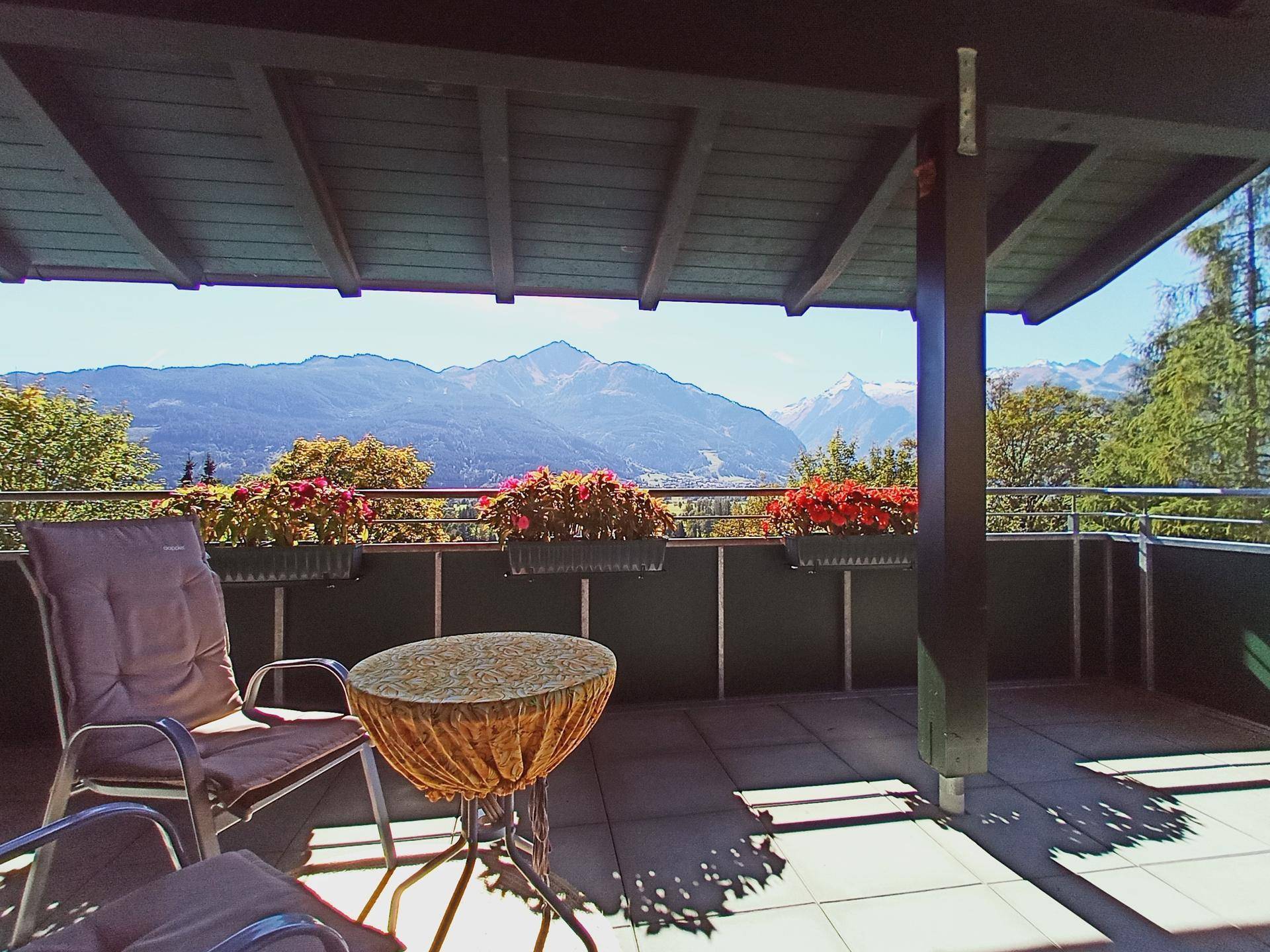 Überdachte Terrasse mit Sitzgelegenheiten und weitem Blick auf die Berge.