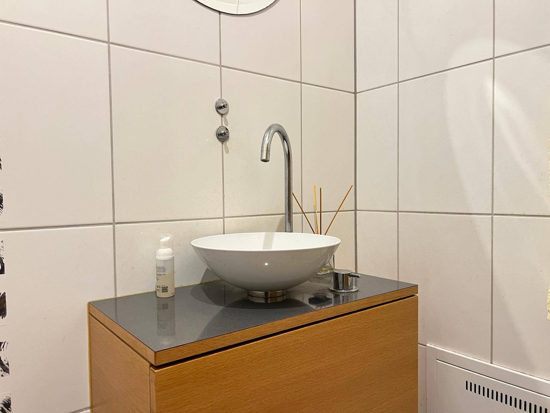 Kleines Gäste-WC mit modernem Aufsatzwaschbecken und weißen Fliesen.