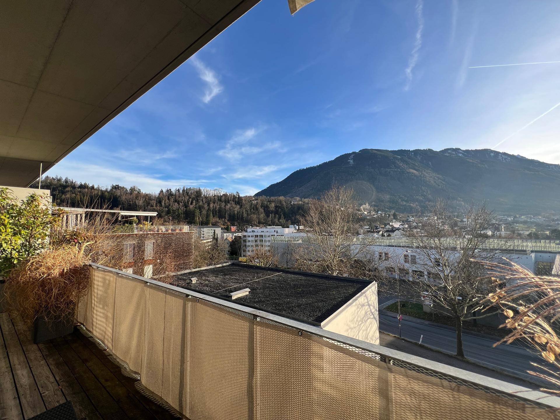 Balkon mit Holzboden und weitem Blick auf die Stadt und die umliegende Berglandschaft.