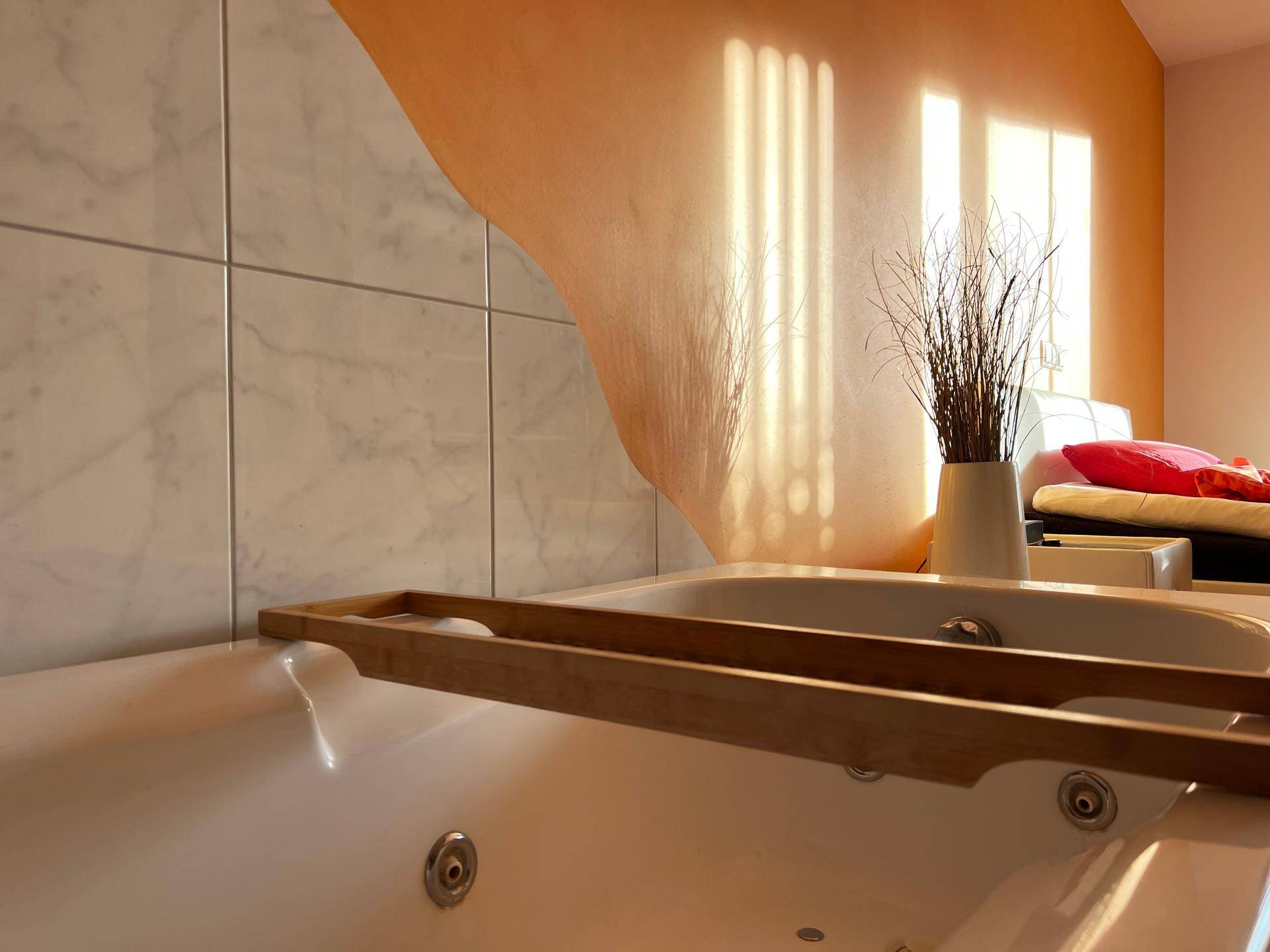 Nahaufnahme einer modernen Badewanne mit Holzablage und Marmorfliesen.