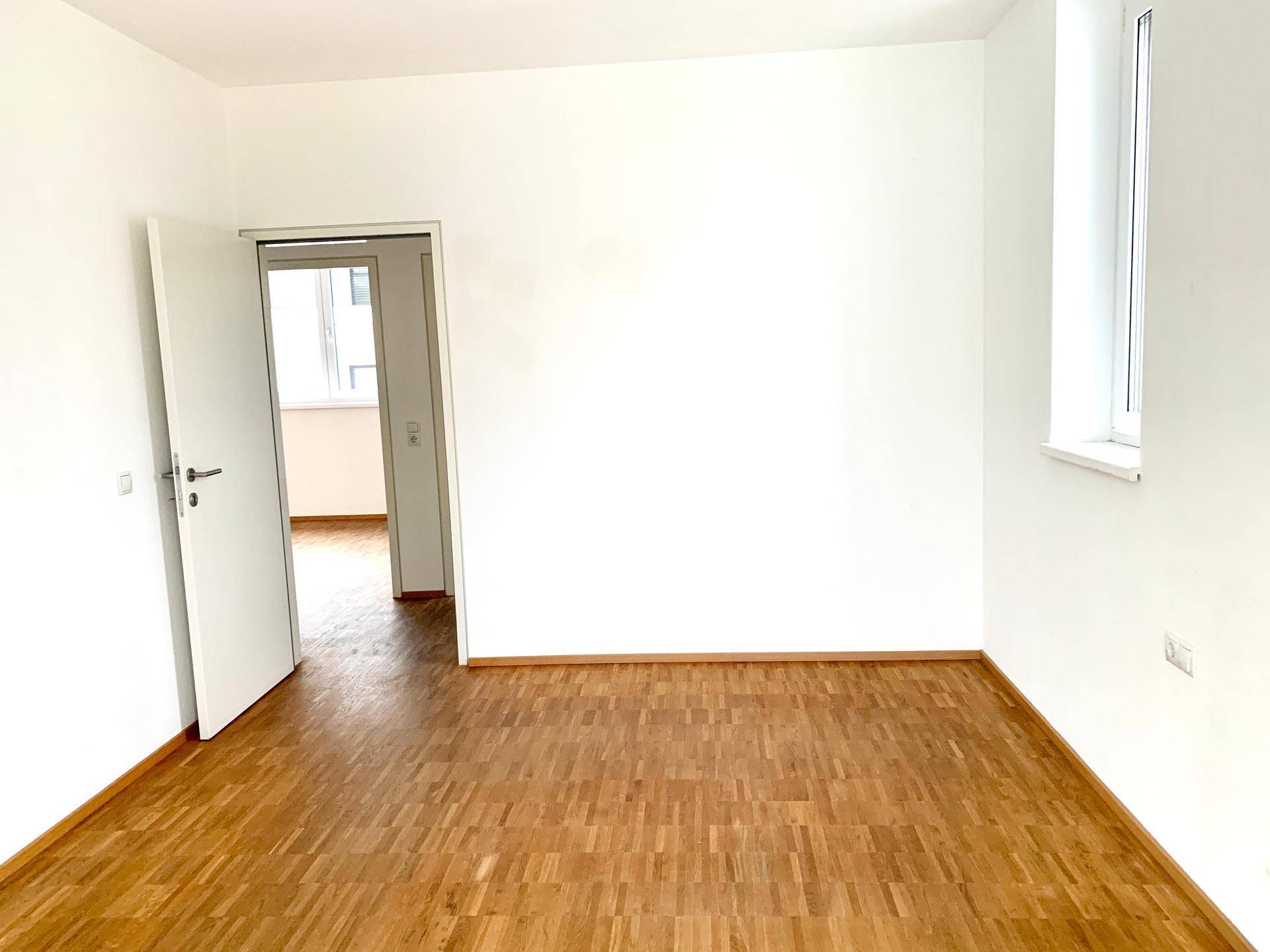 Heller Raum mit Parkettboden und offener Tür, der vielseitig genutzt werden kann.
