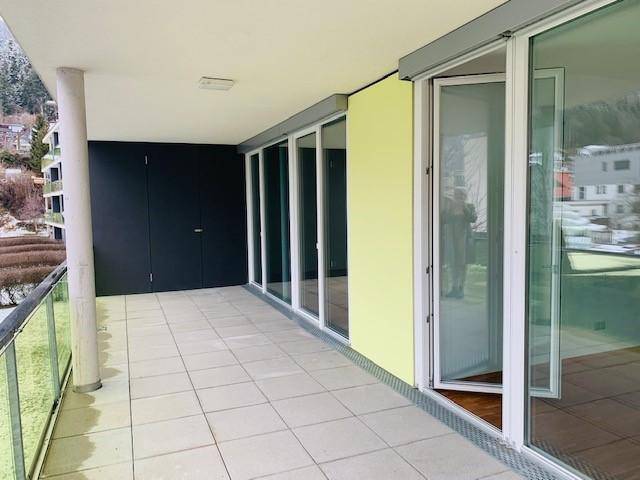 Geräumiger Balkon mit Fliesenboden und Glasgeländer, ideal für entspannte Stunden im Freien.