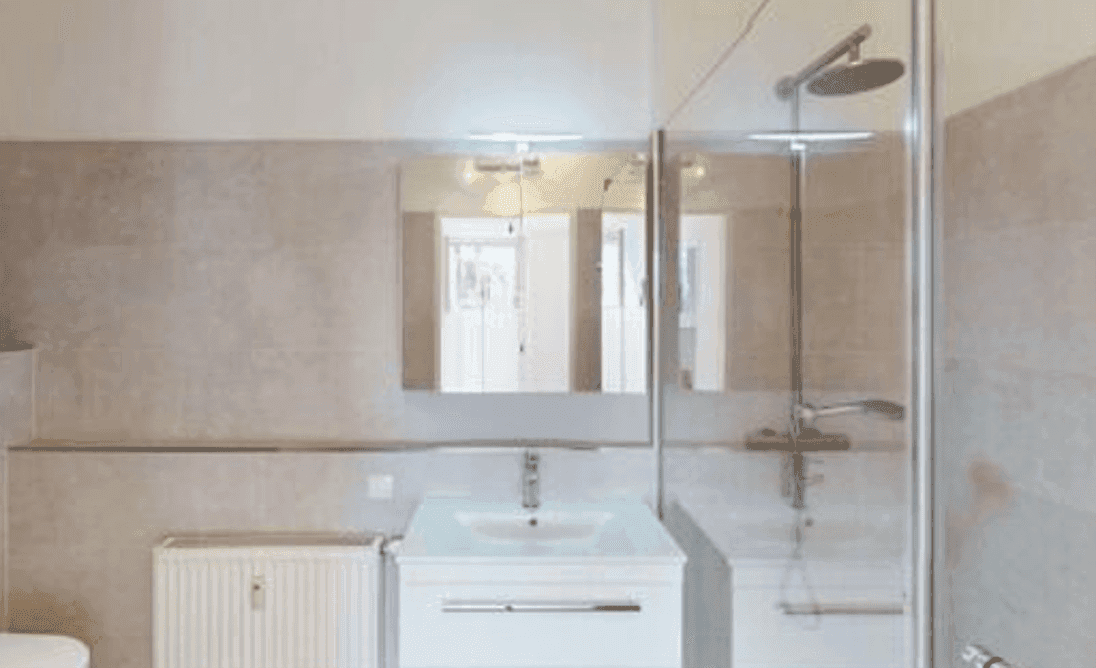 Modernes Badezimmer mit grauen Fliesen, Einzelwaschbecken und einer Duschkabine mit Regendusche.