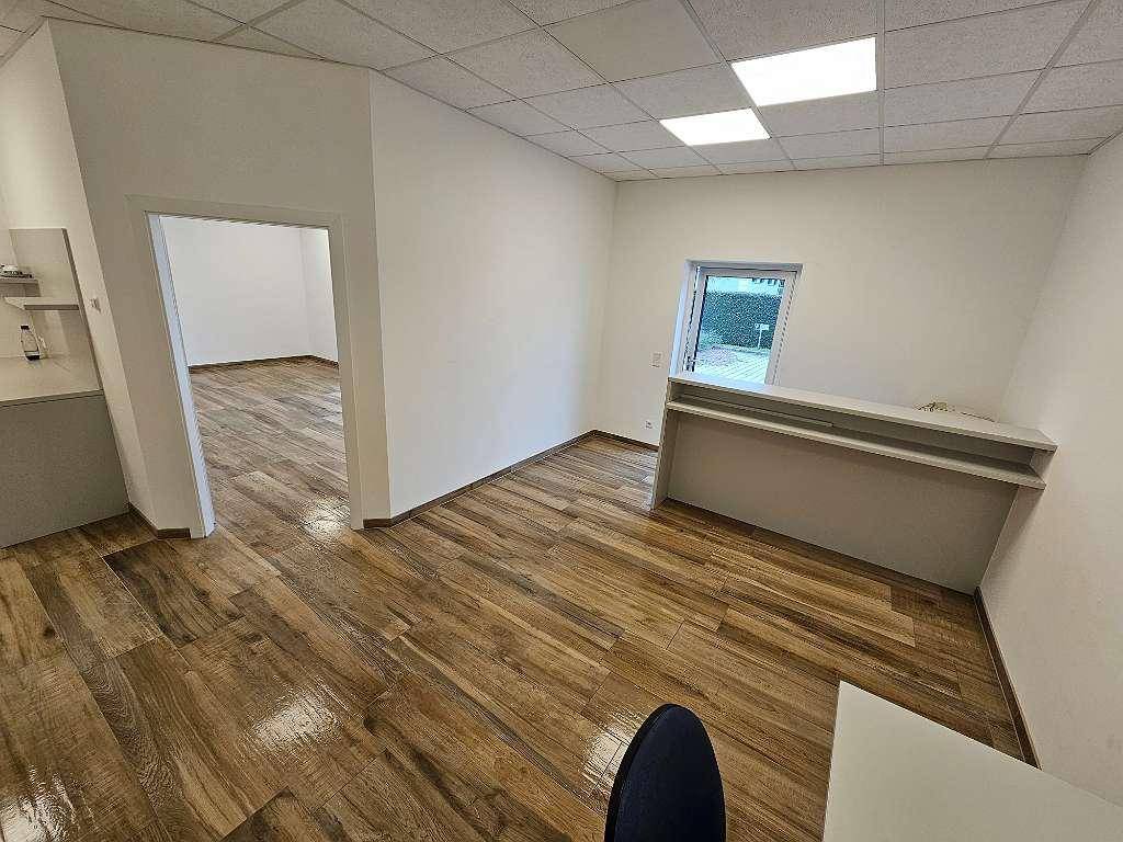 Moderner Büroraum mit Empfangsbereich und Holzfliesenboden, ideal für Kundenempfang und Arbeitsplätze.