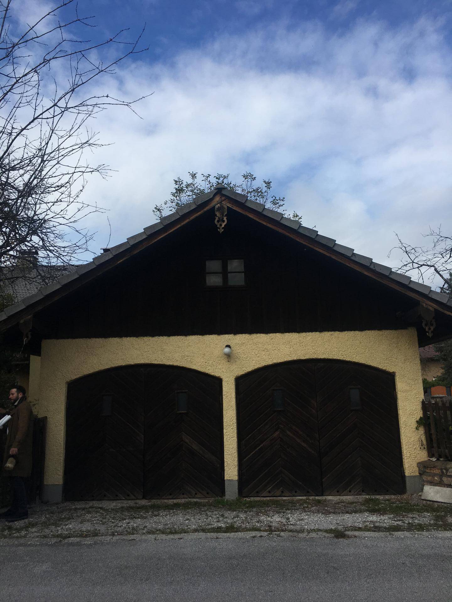 Separate Garage mit zwei großen Holztoren und traditionellem Satteldach.