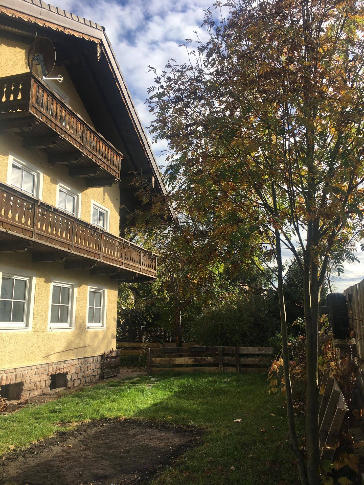Seitenansicht des Hauses mit Balkonen und einem gepflegten Gartenbereich.