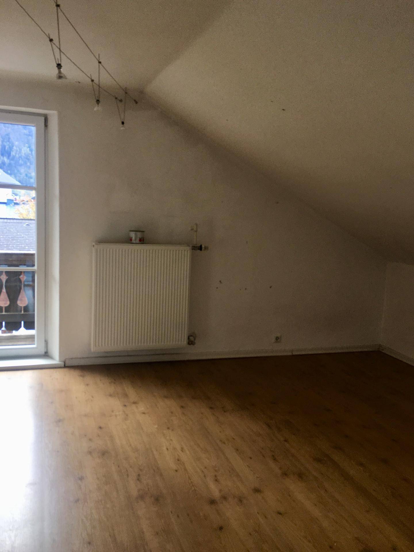 Helles Zimmer im Dachgeschoss mit schräger Decke und Holzboden.
