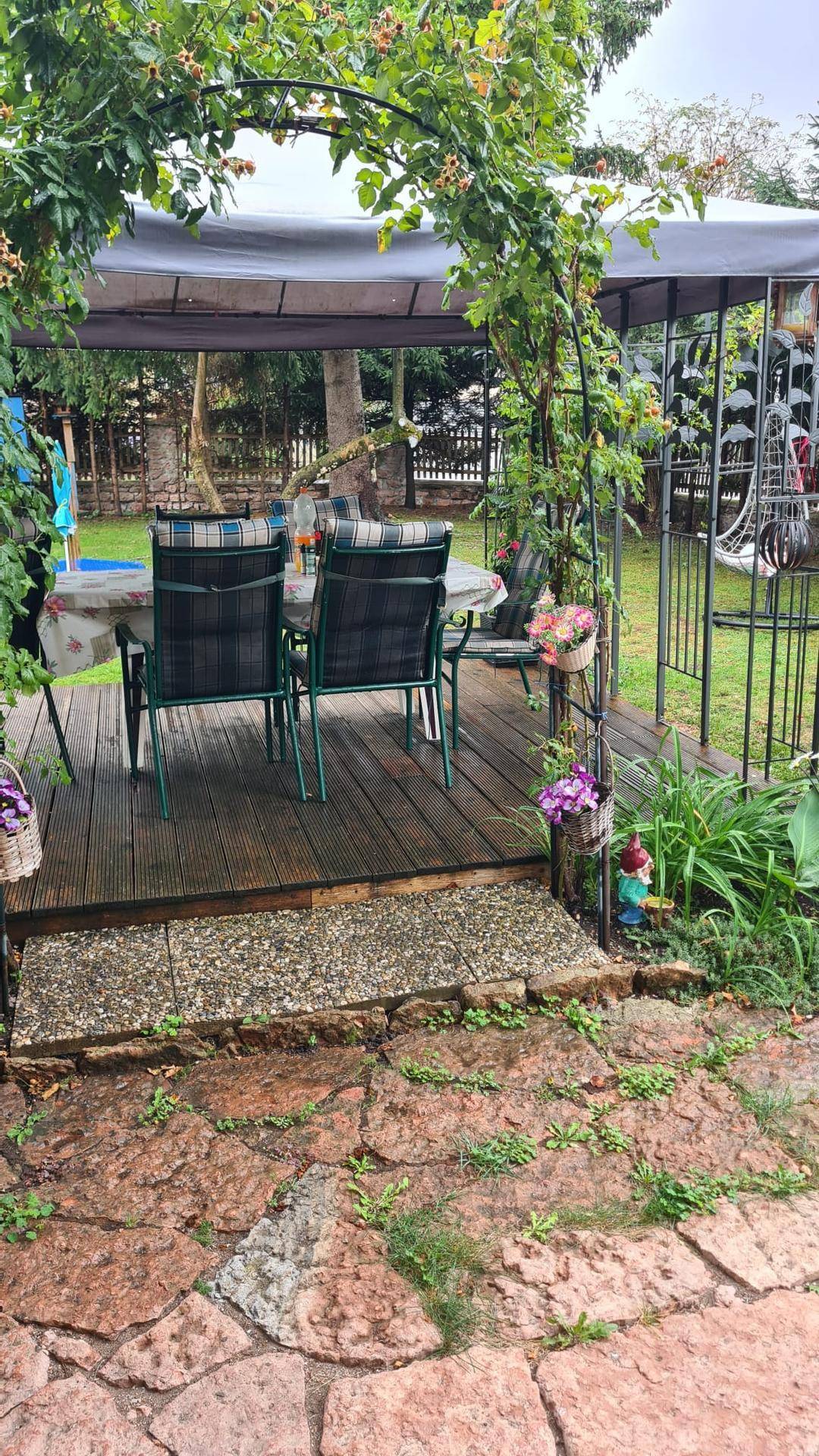 Gemütlicher Außenbereich mit überdachter Terrasse, Esstisch und Gartenblick.
