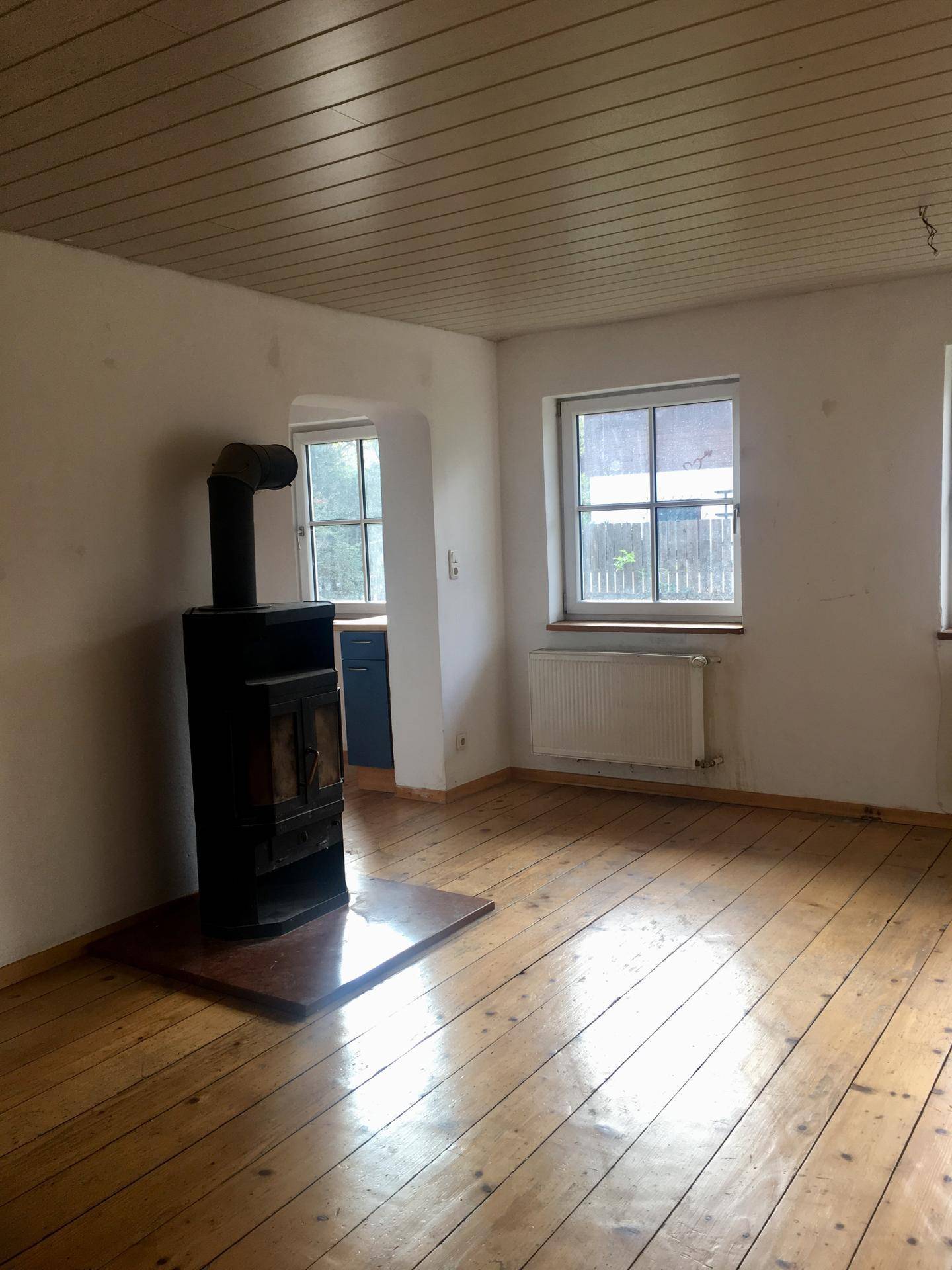 Geräumiges Wohnzimmer mit Holzdielenboden und einem traditionellen Holzofen.