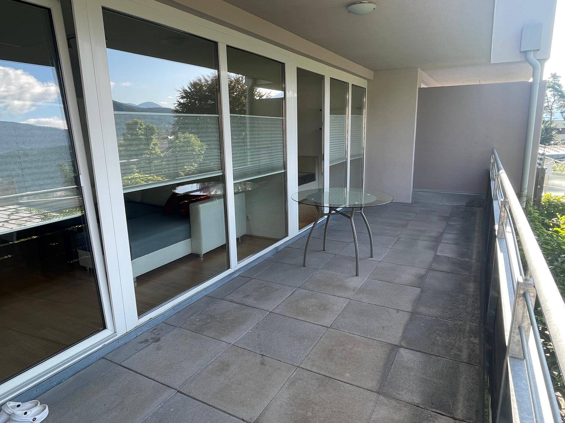 Geräumiger Balkon mit Fliesenboden, Glasgeländer und Bergblick.