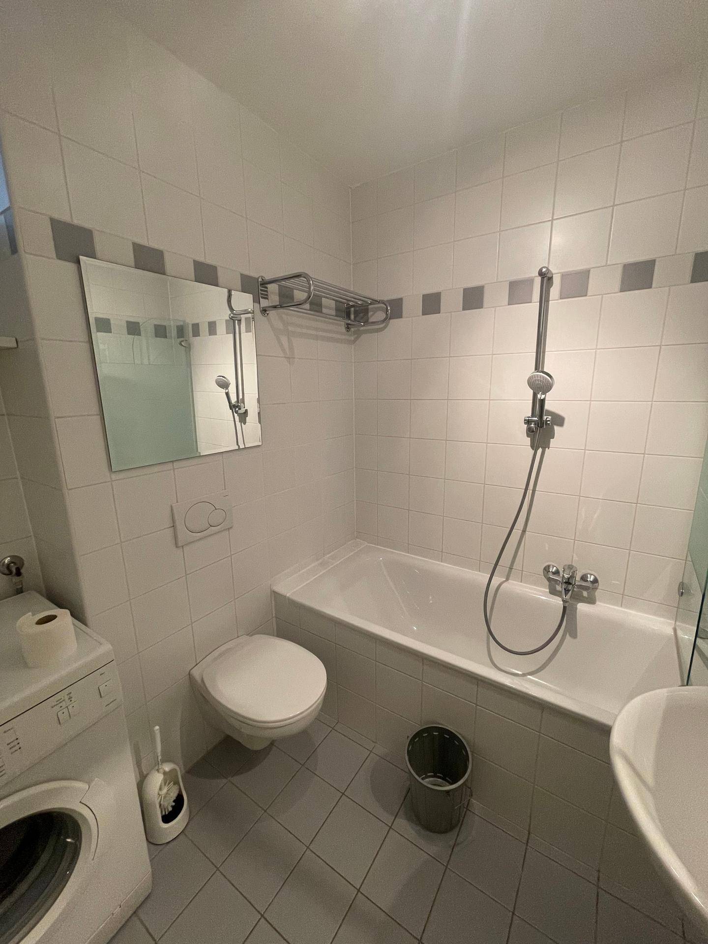 Modern gefliestes Badezimmer mit Badewanne, Dusche und Waschbecken.