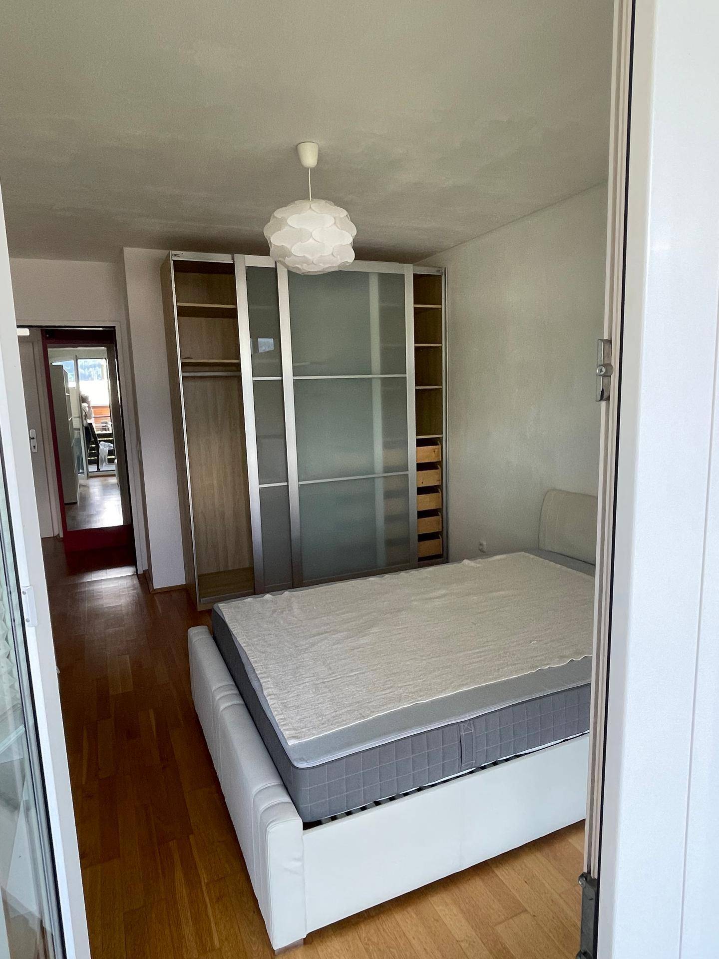 Schlafzimmer mit Doppelbett, großem Kleiderschrank und Holzboden.