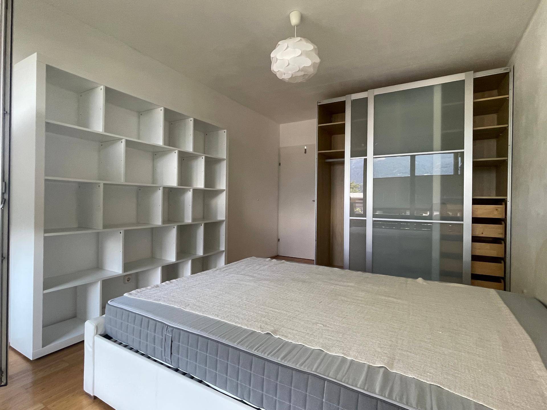 Schlafzimmer mit Doppelbett, großem Kleiderschrank und Bücherregal.