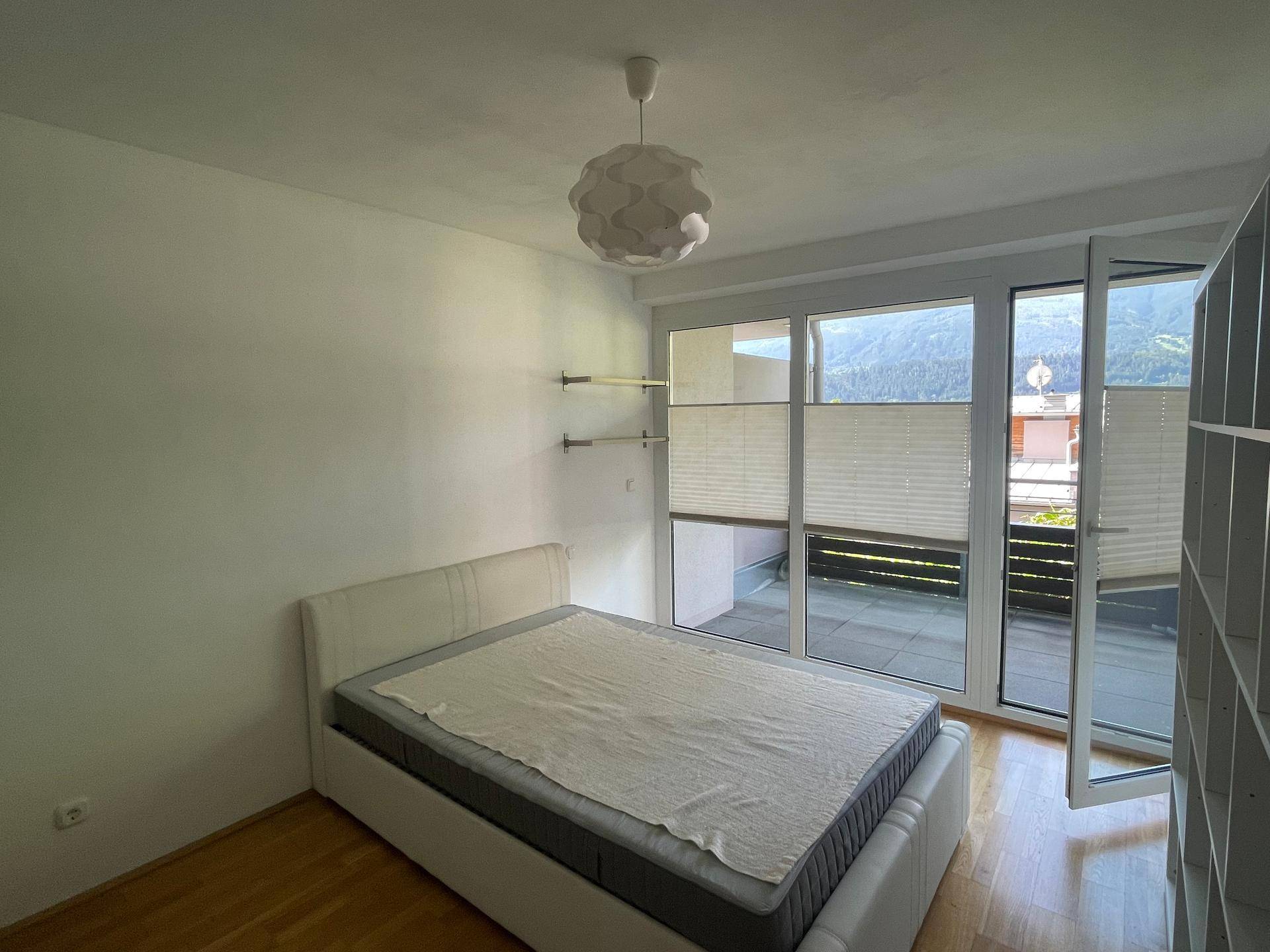 Helles Schlafzimmer mit Balkonzugang, Bergblick und Holzboden.