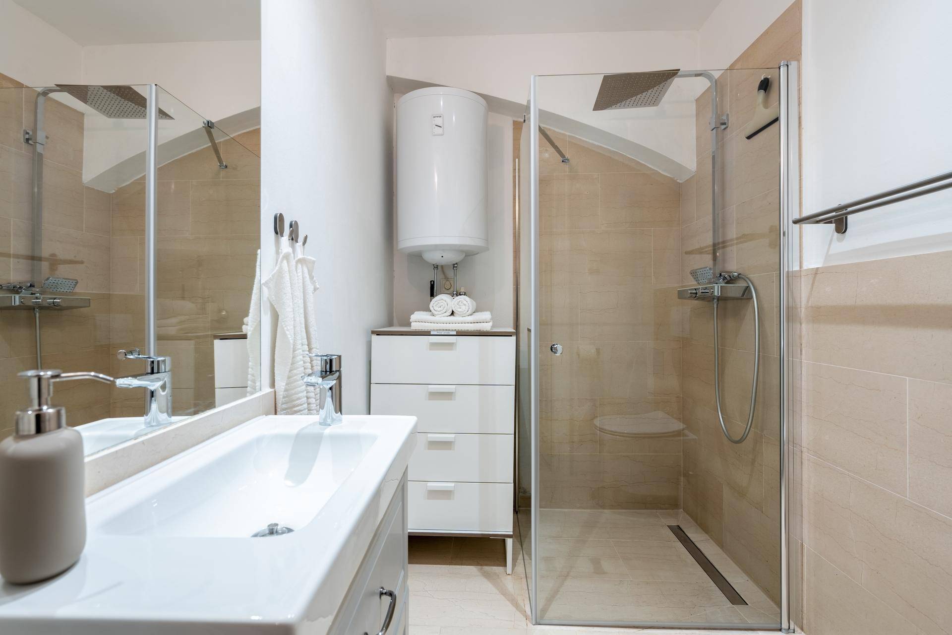 Modernes Badezimmer mit ebenerdiger Dusche, Einzelwaschbecken und beigefarbenen Fliesen.