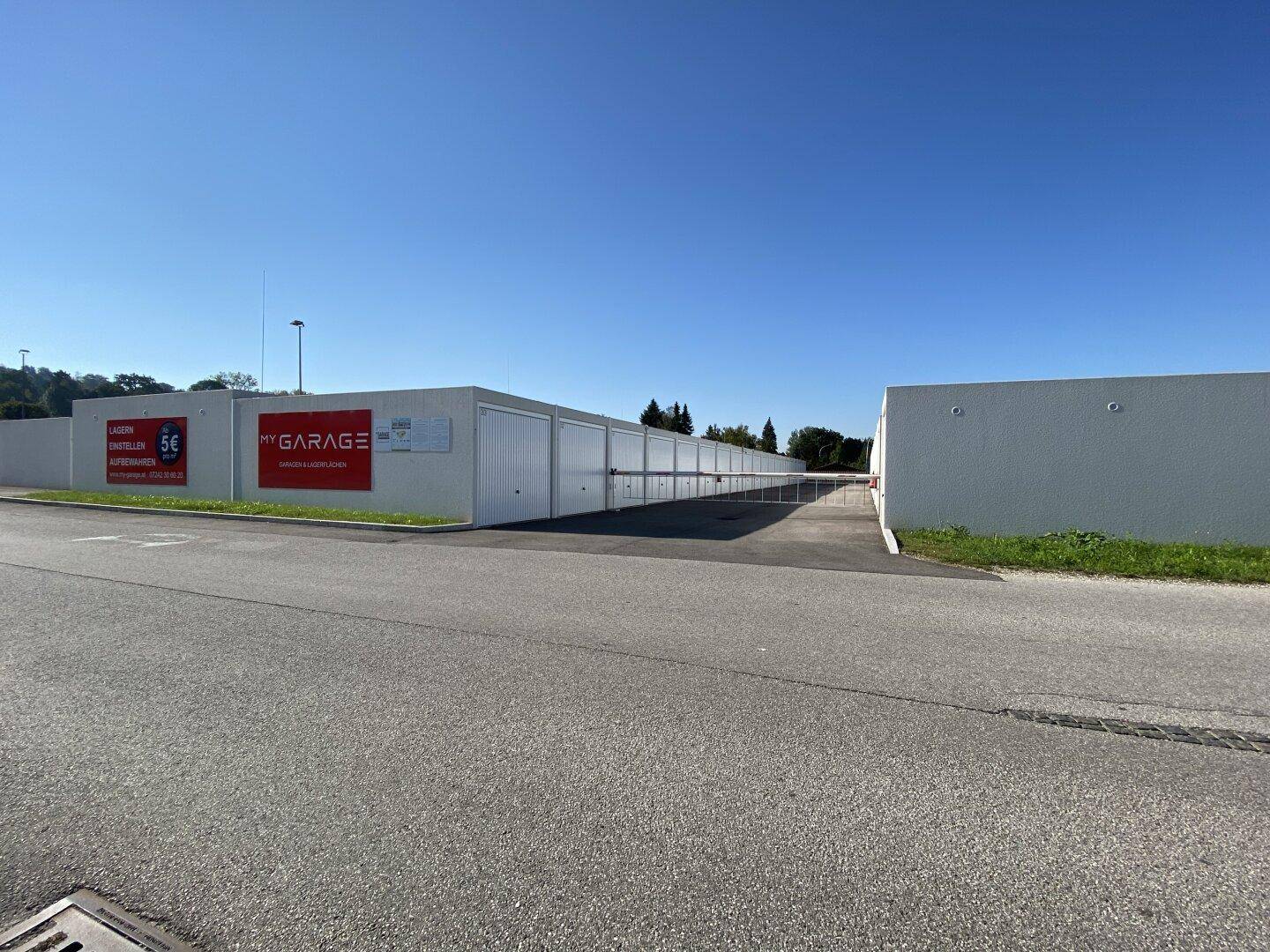 Außenansicht der Lagerhallen mit weißen Garagentoren und Werbeschildern an der Straße.