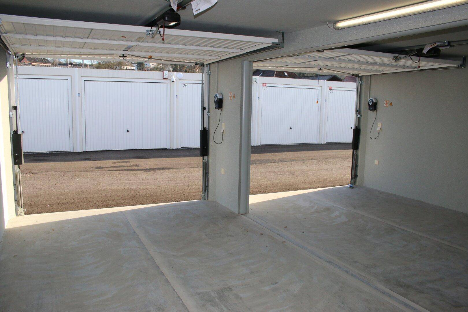 Zwei offene Garagenboxen mit Blick auf weitere Garagentore und den Außenbereich.