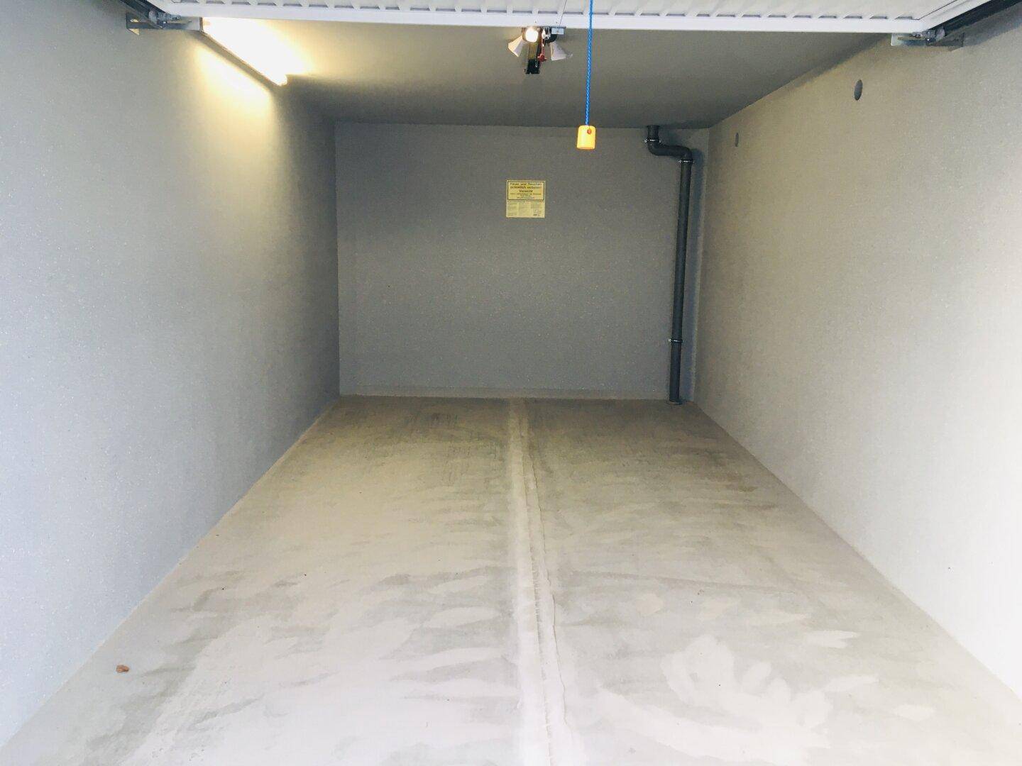 Leere, saubere Lagereinheit mit Betonboden und Beleuchtung, bereit zur Nutzung.