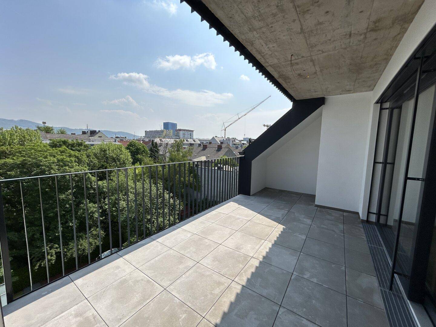 Geräumiger Balkon mit Fliesenboden und weitem Blick über die Stadt.