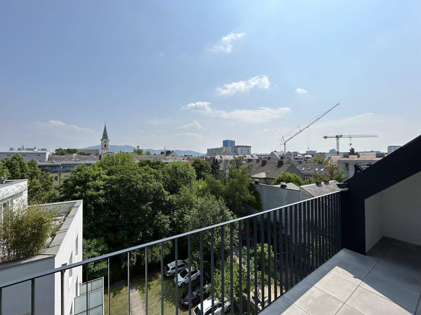 Weitläufiger Blick vom Balkon über die grüne Umgebung und die Stadt.