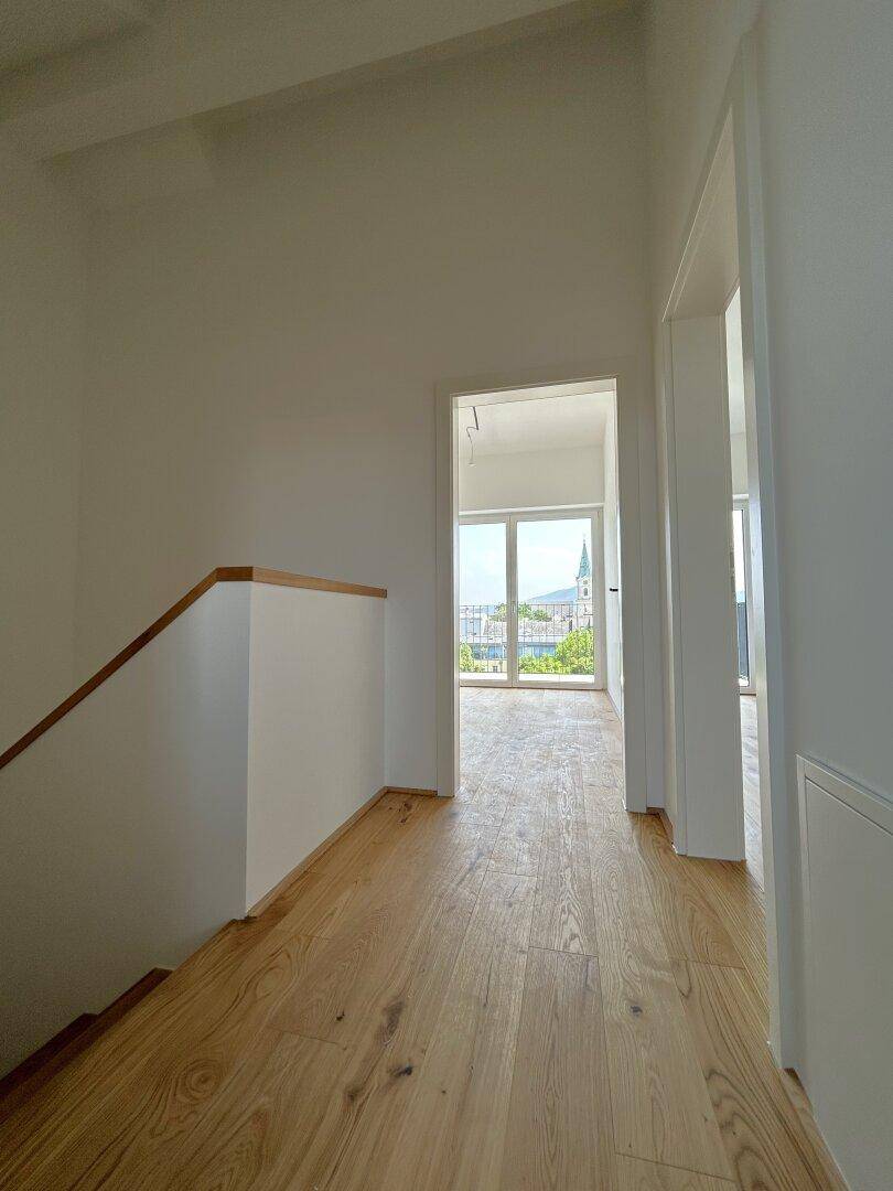 Heller Flur mit Eichenparkett, der zu einem Raum mit weitem Stadtblick führt.