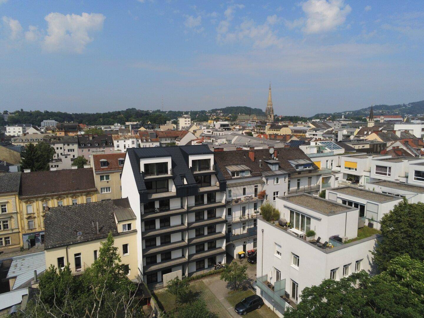 Panoramablick auf den modernen Neubau und die umliegende Stadtlandschaft mit Kirchturm.