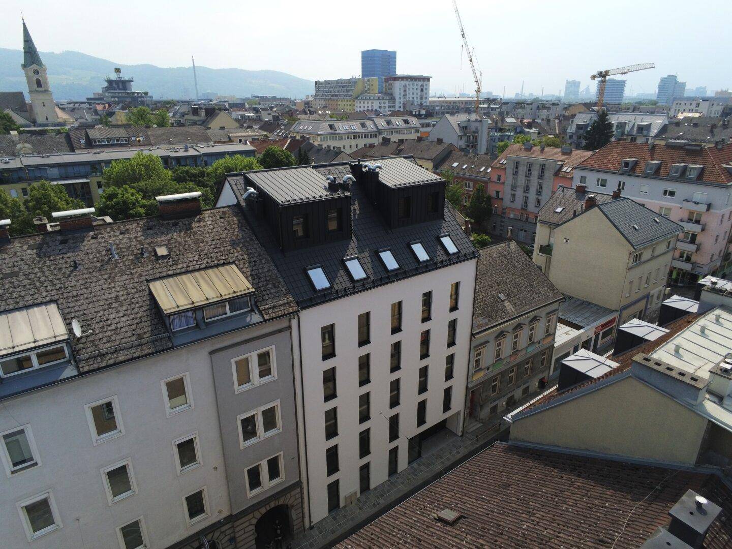 Luftaufnahme des modernen Neubaus inmitten der städtischen Bebauung mit Weitblick.