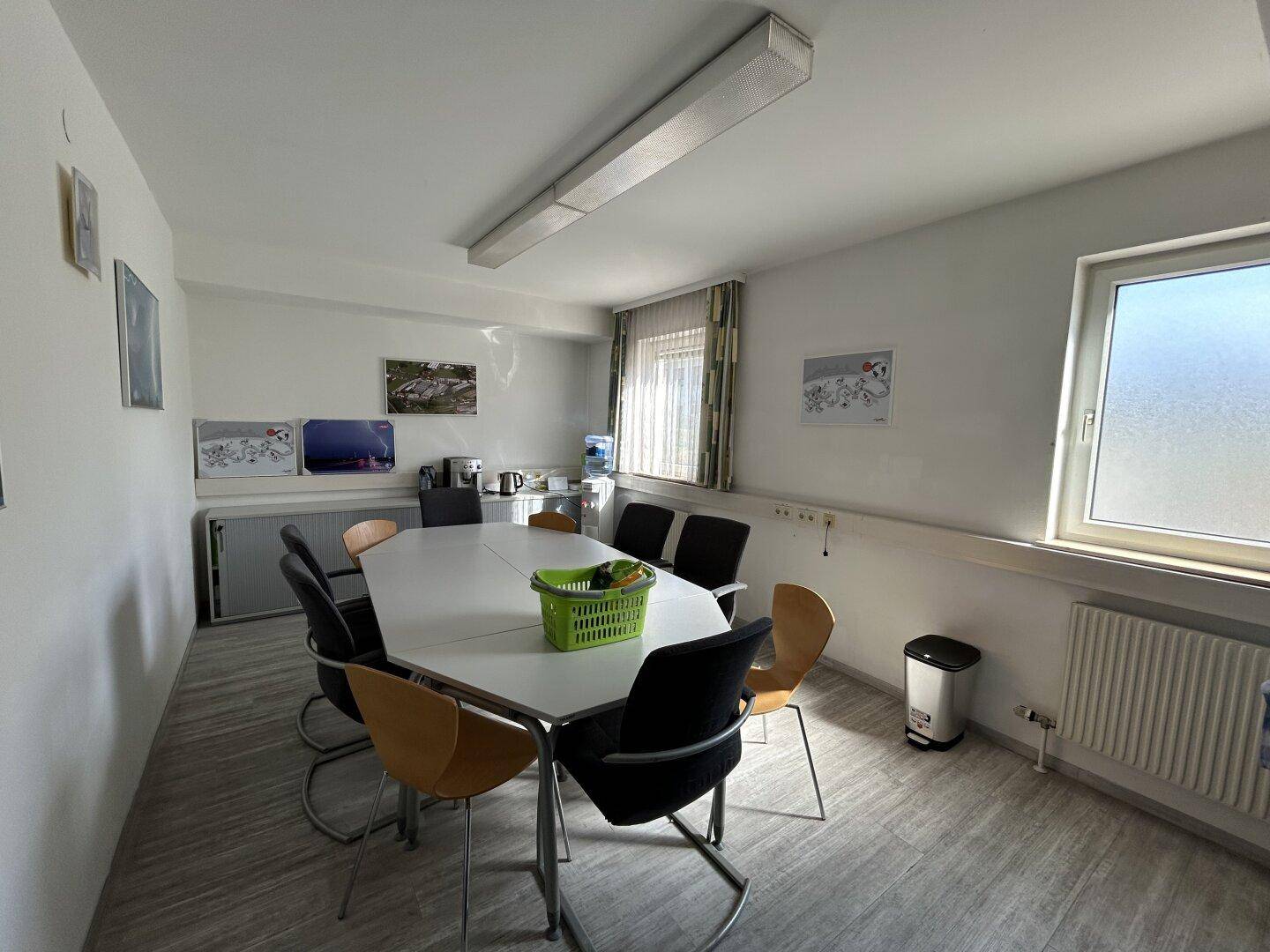 Heller Konferenzraum mit einem großen achteckigen Tisch, modernen Stühlen und einem Fenster für Tageslicht.