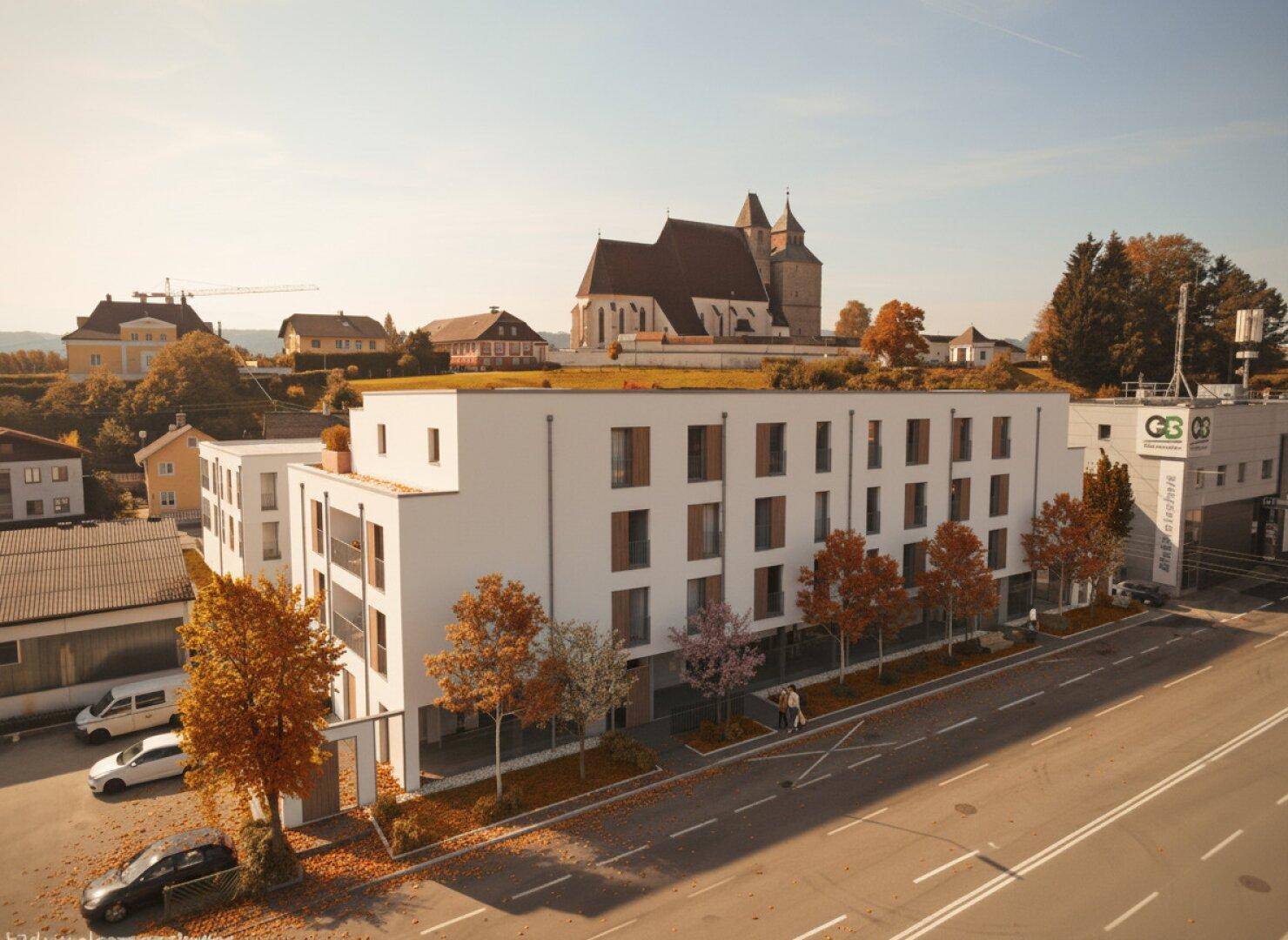 Moderne Wohngebäude mit klarer Architektur und begrüntem Dach in einer städtischen Umgebung mit historischer Kirche.