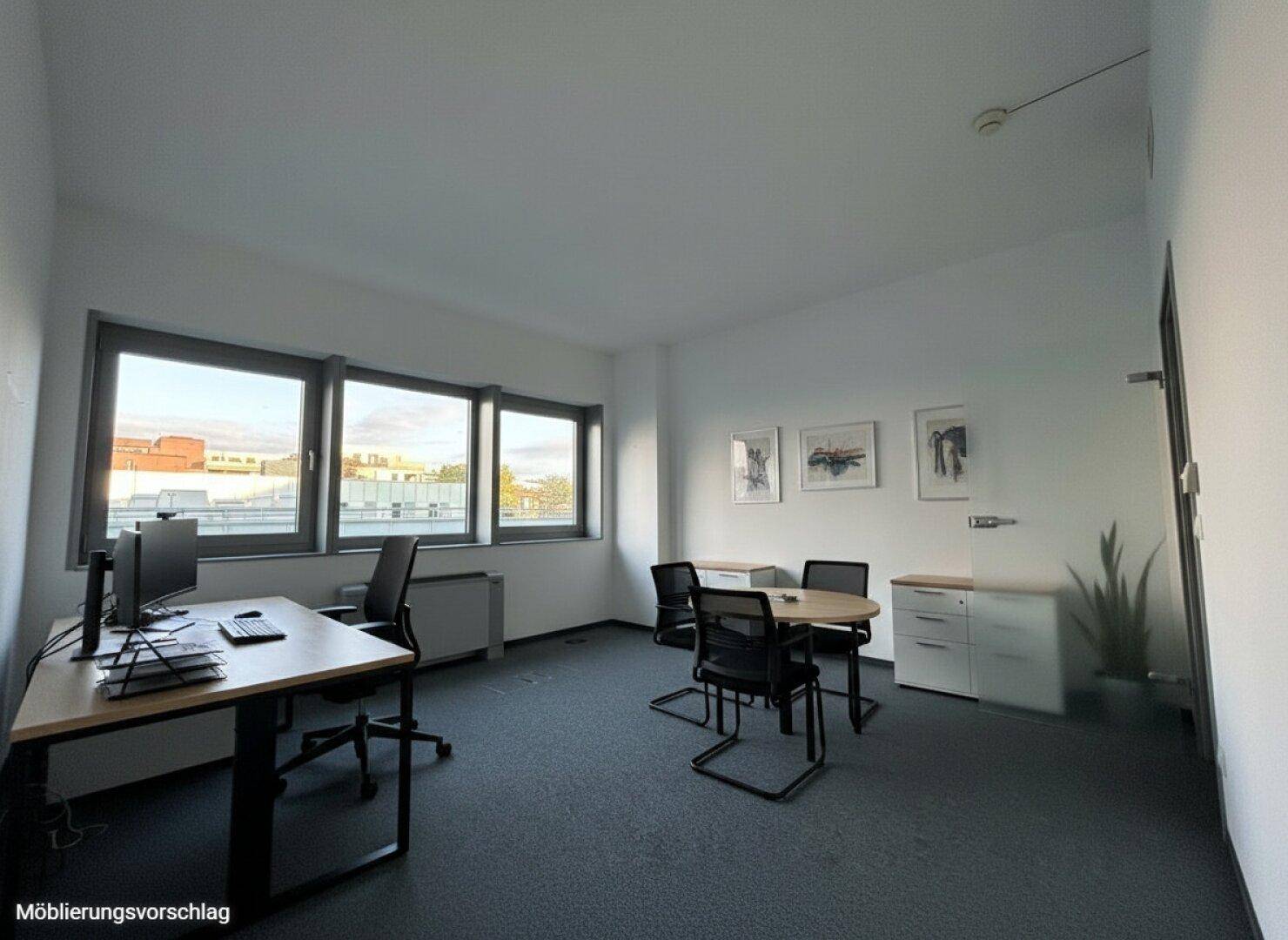 Helles Einzelbüro mit großzügigen Fenstern, einem Schreibtisch und zusätzlichem Besprechungstisch.